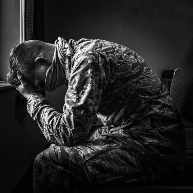 a man sitting in front of a window with his head in his hands, a picture, military composure, grieving. intricate, man standing, uploaded