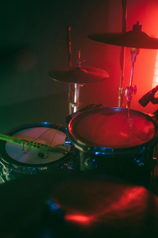 a drum set up in front of a red light, pexels, blue and green and red tones, vibrating, medium detail, indoor picture