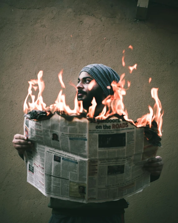 a man holding a burning newspaper in front of his face, an album cover, pexels contest winner, turban, fire!! full body, lgbtq, snapchat photo