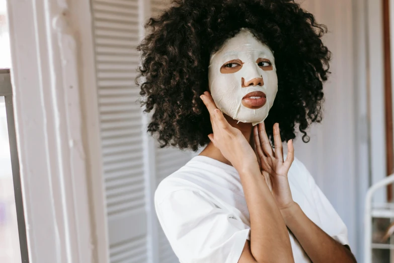 a woman with a white mask on her face, trending on pexels, brown skin like soil, manuka, woman with black hair, clear [bronze] face