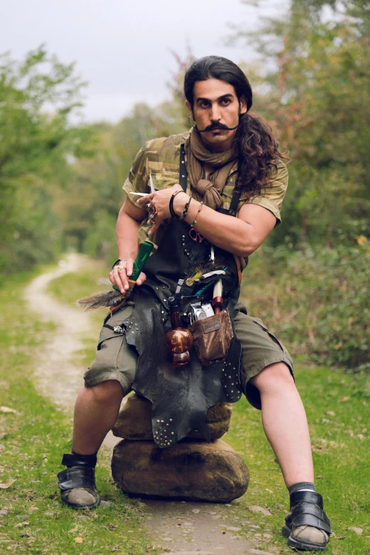 a man with long hair sitting on a rock, inspired by János Saxon-Szász, renaissance, steampunk style weapons, unibrow, real life photo of a syrian man, long curly green hair