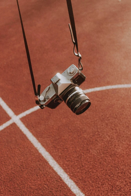 a camera hanging from a string on a track, inspired by Alexander Rodchenko, unsplash contest winner, on a soccer field, tennis court, playful composition, short telephoto