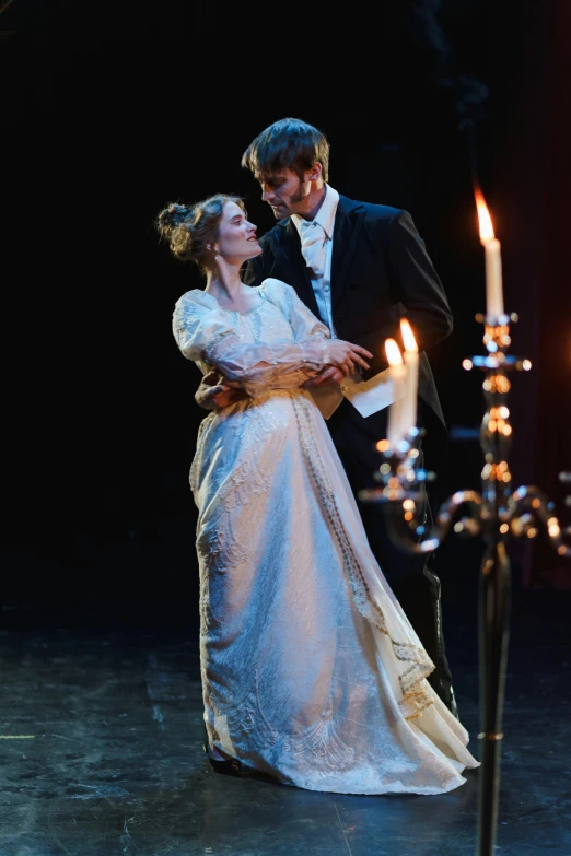 a man and a woman standing next to each other, a portrait, by Alice Mason, romanticism, theatrical lighting, in a room full of candles, dancing with each other, both wearing victorian clothes