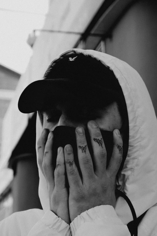 a man in a hoodie covers his face with his hands, a black and white photo, inspired by Seb McKinnon, alternate album cover, aesthetic!!!!!!!!!!, bladee from drain gang, he wears dark visors