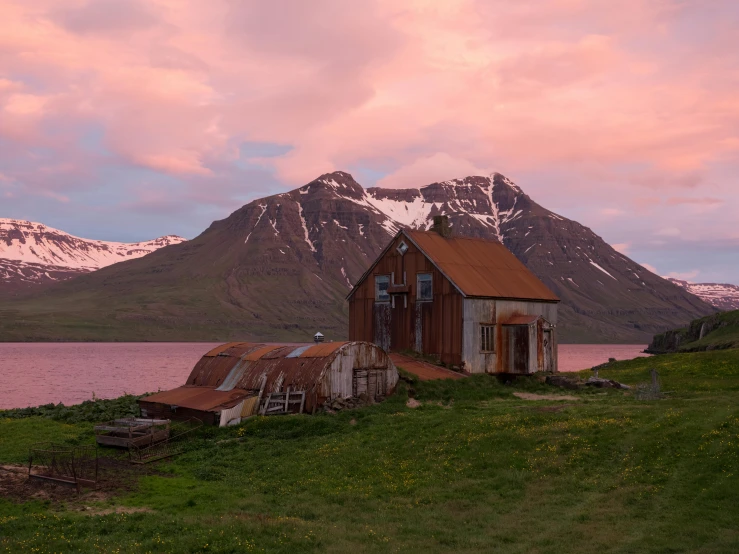 a house sitting on top of a lush green hillside, by Þórarinn B. Þorláksson, pexels contest winner, brown and pink color scheme, predawn, old cowboy in the arctic, in the style wes anderson