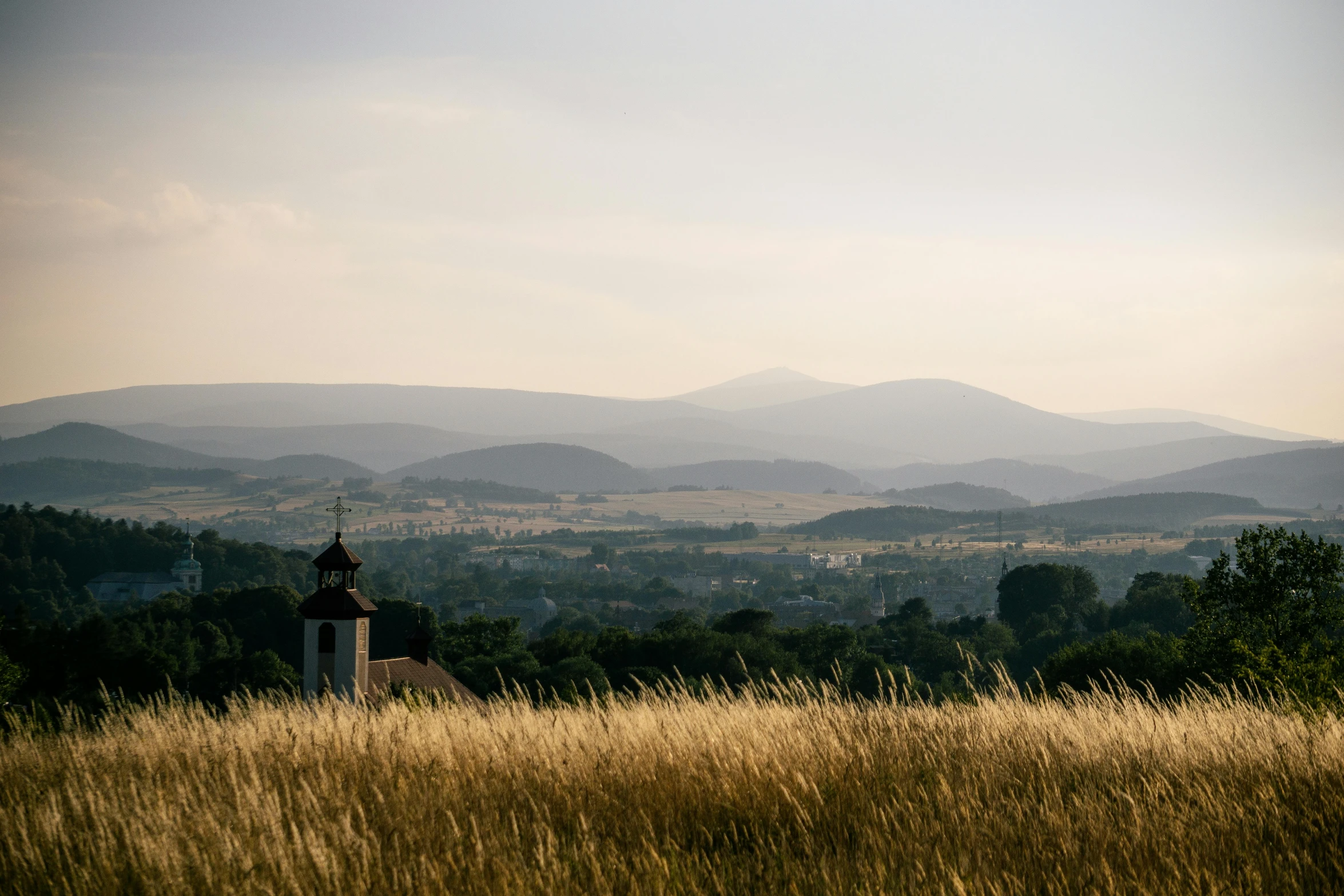 a church in a field with mountains in the background, pexels contest winner, austro - hungarian, shot on hasselblad, distance view, summer setting