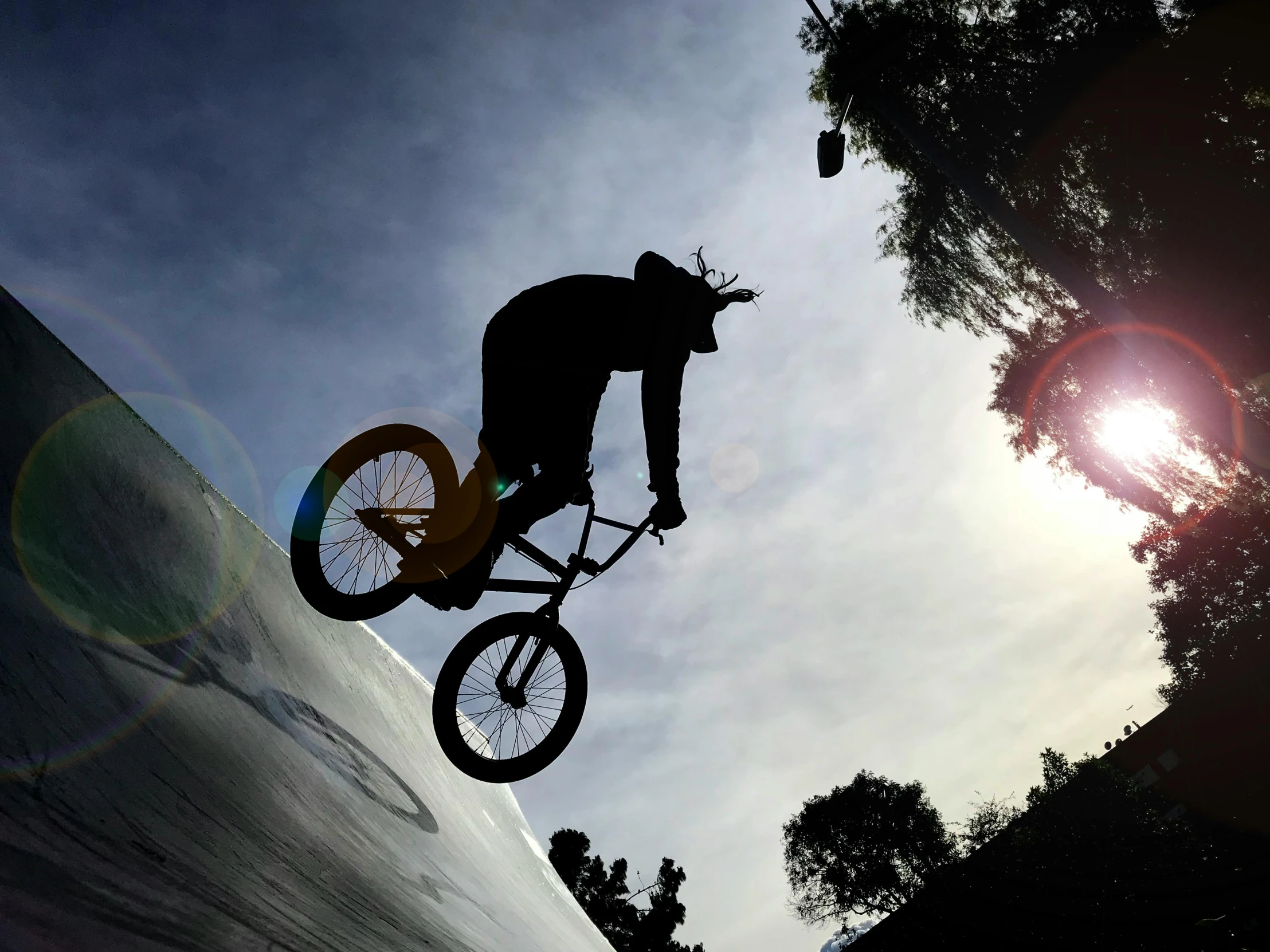 a man riding a bike up the side of a ramp, a picture, pexels contest winner, extreme backlighting, over the tree tops, avatar image, spaghettification