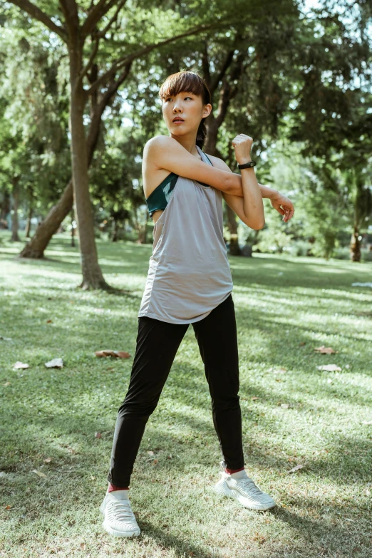 a woman standing in a park holding a baseball bat, by Natasha Tan, pexels contest winner, wearing : tanktop, dynamic active running pose, malaysian, grey