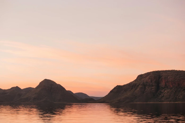 a body of water with mountains in the background, by Lee Loughridge, pexels contest winner, pink golden hour, grey, slightly minimal, warm summer nights