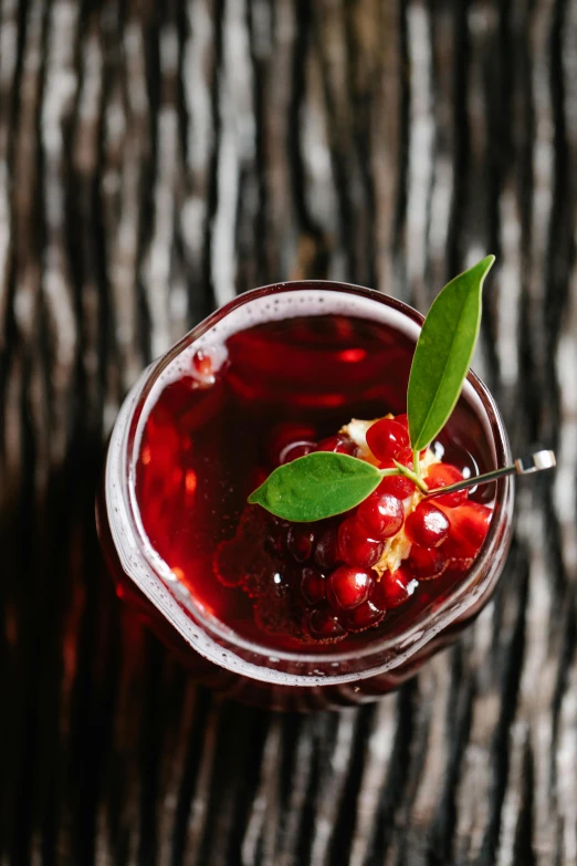 a drink sitting on top of a wooden table, submerged in cranberries, botanicals, innovative, seams