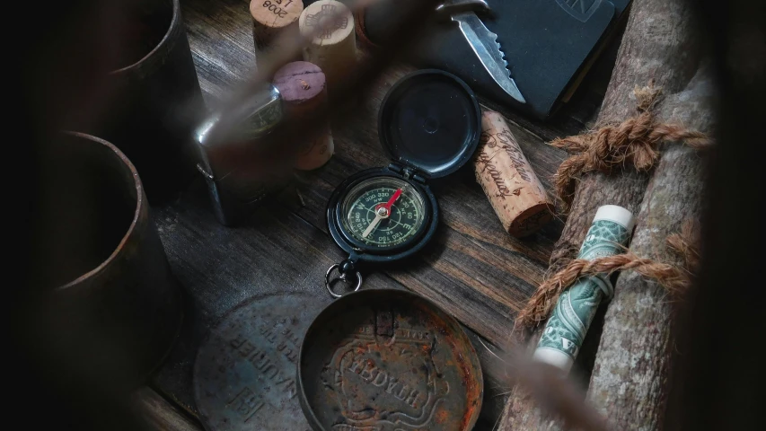 a compass sitting on top of a wooden table, various items, some rust, curated collections, secret underground lab