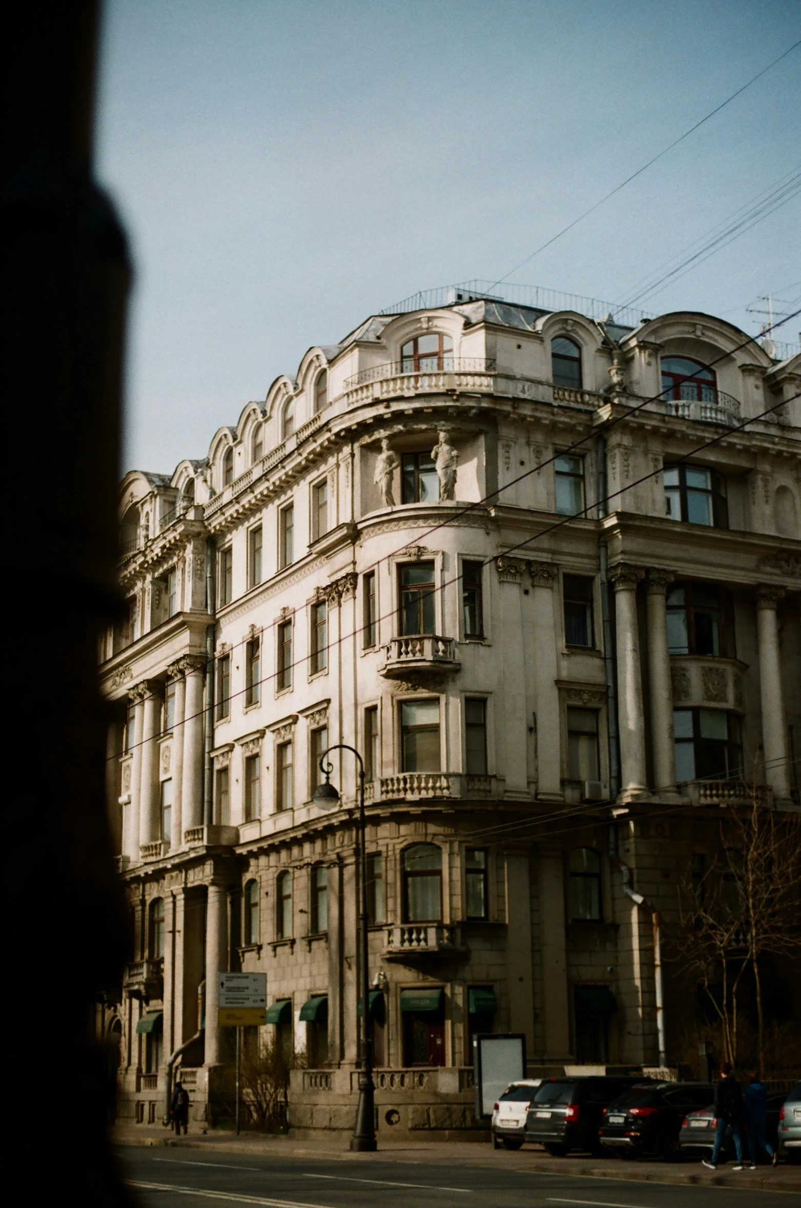 a tall building sitting on the side of a street, inspired by Vasily Surikov, unsplash, art nouveau, sunny bay window, analogue photo low quality, cinematic shot ar 9:16 -n 6 -g, neo classical architecture