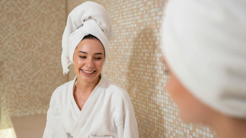 a woman standing in front of a mirror with a towel on her head, turning her head and smiling, profile image, dirty linen robes, paradise garden massage