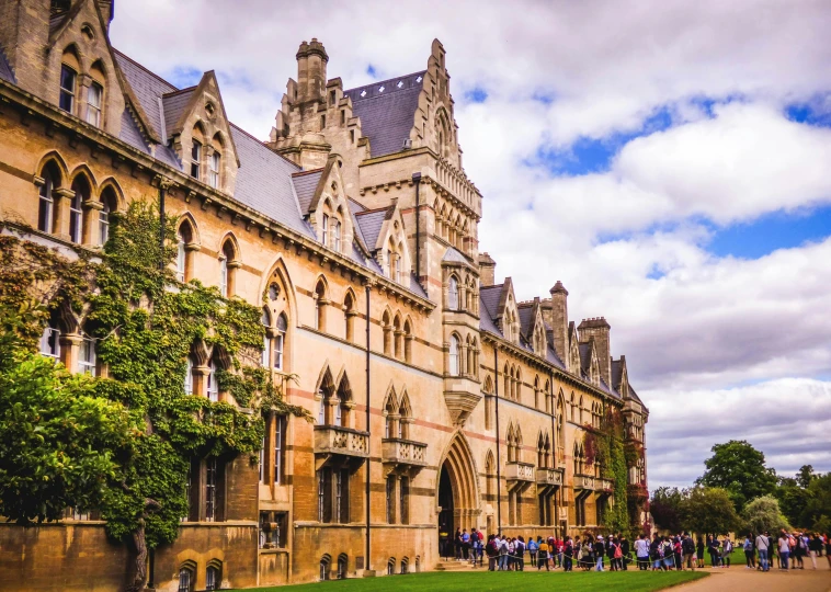 a group of people standing in front of a building, by Rachel Reckitt, pexels contest winner, academic art, gothic building style, panoramic, during autumn, pyramid surrounded with greenery