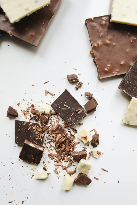 a bunch of pieces of chocolate sitting on top of a table, by Jessie Algie, on a pale background, cheesy, bark, epicurious