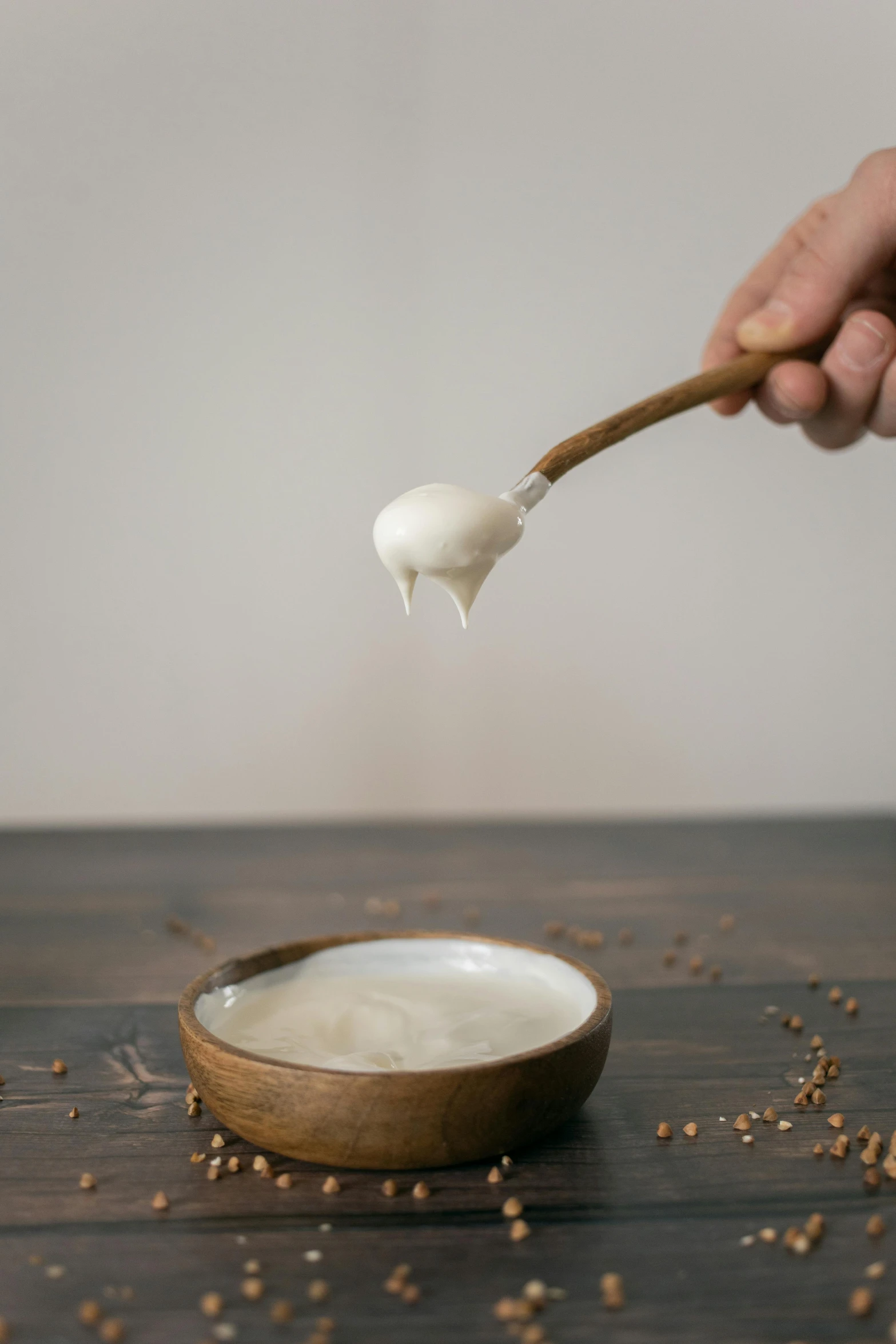 a person holding a spoon over a bowl of yogurt, inspired by Li Di, on a wooden tray, glaze, full product shot, thumbnail