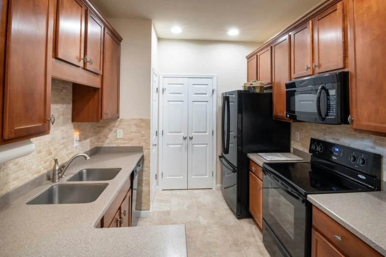 a kitchen with wooden cabinets and black appliances, by Carey Morris, unsplash, 2 5 6 x 2 5 6 pixels, 3/4 view from below, apartment, granite