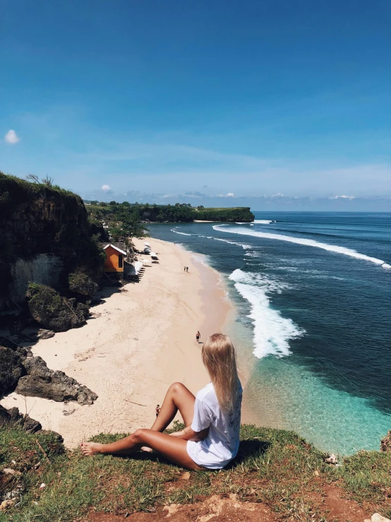 a woman sitting on top of a hill next to the ocean, bali, profile image, flatlay, white sandy beach