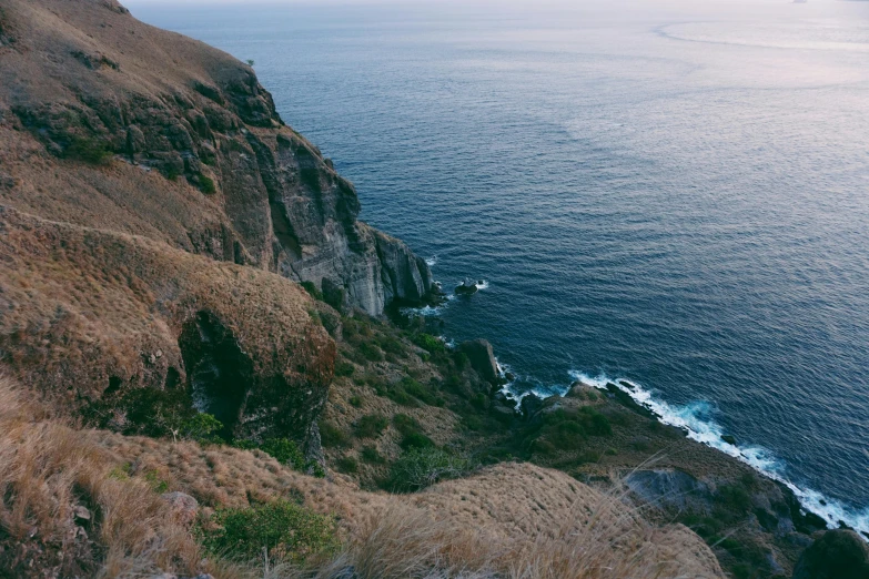 a man standing on top of a cliff next to the ocean, pexels contest winner, philippines, hillside, highly detailded, shot on hasselblad