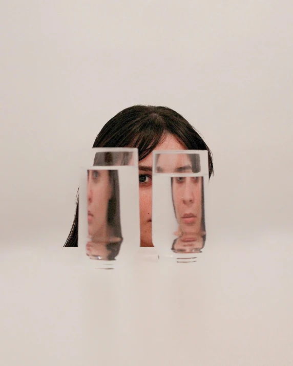 a woman with two glasses of water in front of her face, an album cover, inspired by Marina Abramović, promotional photo, clear shapes, three dimensions, official product photo