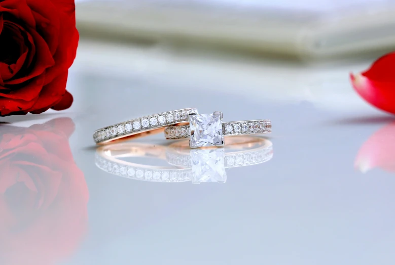 a couple of rings sitting on top of a table next to a rose, by Julian Allen, pexels contest winner, made of diamond, rectangle, white background : 3, square