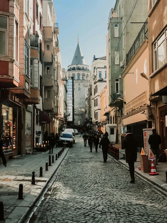 a group of people walking down a cobblestone street, a photo, pexels contest winner, art nouveau, turkey, with towers, 🚿🗝📝