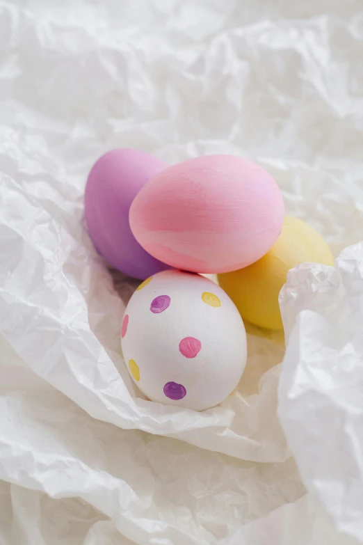 a group of three eggs sitting on top of a white sheet, lots of pastel colour, decorations, up close, colour photograph