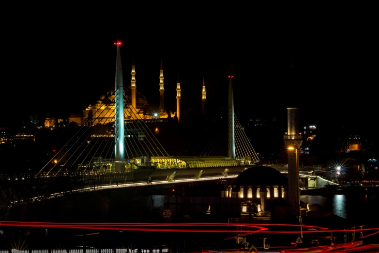 a bridge over a body of water at night, an album cover, by Ibrahim Kodra, pexels contest winner, hurufiyya, minarets, traffic with light trails, gold, turkey