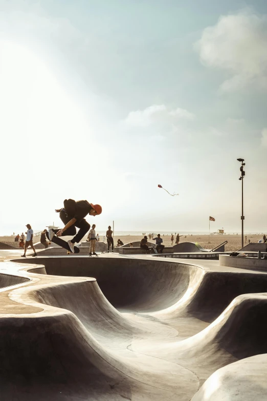 a man riding a skateboard up the side of a ramp, unsplash contest winner, concrete art, victorian arcs of sand, frank gehry, floating in mid - air, santa monica beach