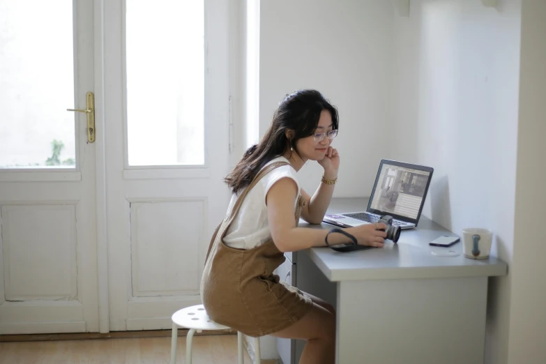 a woman sitting at a desk using a laptop computer, by Jang Seung-eop, pexels contest winner, brown and white color scheme, full body image, kakar cheung, ad image