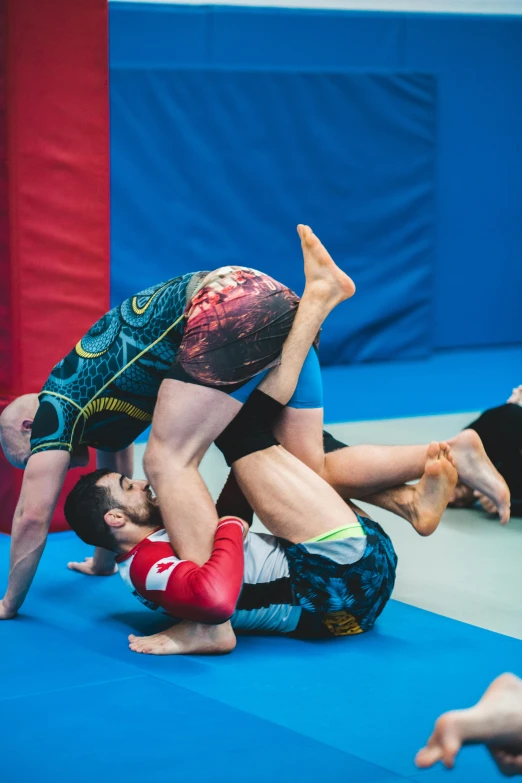 a group of men standing on top of a blue mat, epic wrestling combat, alberto seveso and dan mccaw, medium close shot, triangle