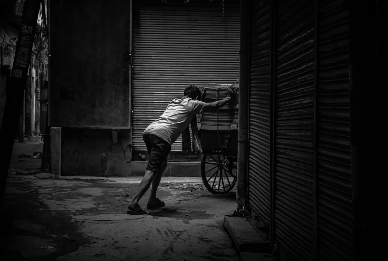 a black and white photo of a man pushing a bike, by Ibrahim Kodra, pexels contest winner, cart, trapped in the backrooms, india, g cgsociety