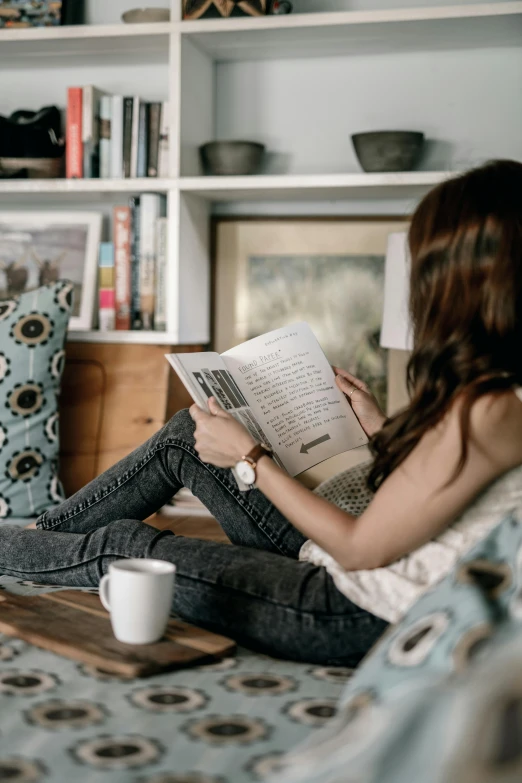 a woman sitting on a couch reading a book, by Carey Morris, pexels contest winner, happening, sitting on a desk, joanna gaines, dwell, student