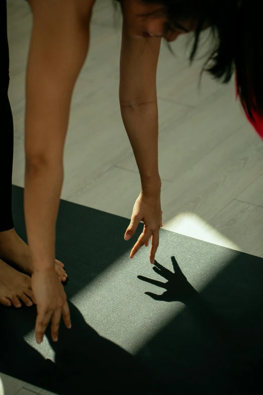 a woman doing a handstand on a yoga mat, by Carey Morris, pexels contest winner, reaching out to each other, deep shadow, hands, low quality photo