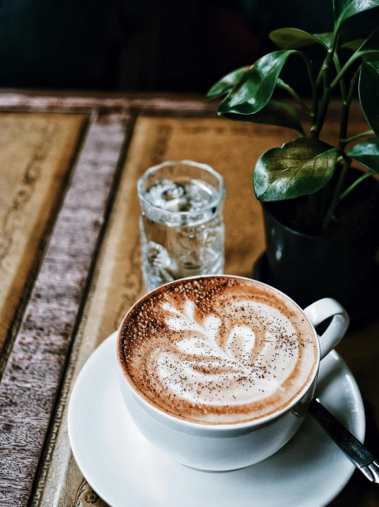 a cup of coffee sitting on top of a wooden table, by Niko Henrichon, trending on unsplash, renaissance, an alien drinking horchata, inside a french cafe, thumbnail, multiple stories