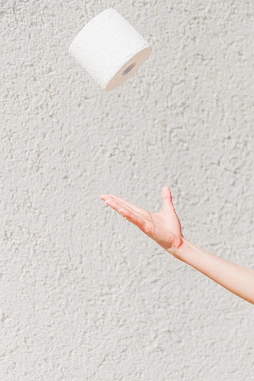 a woman throwing a roll of toilet paper into the air, unsplash, lamp, high detail of a hand, plain background, on a wall