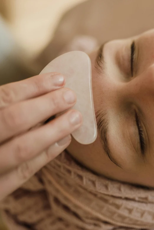 a woman that is laying down with a brush in her hand, a digital rendering, trending on pexels, plasticien, square facial structure, soft pads, crystal, spa