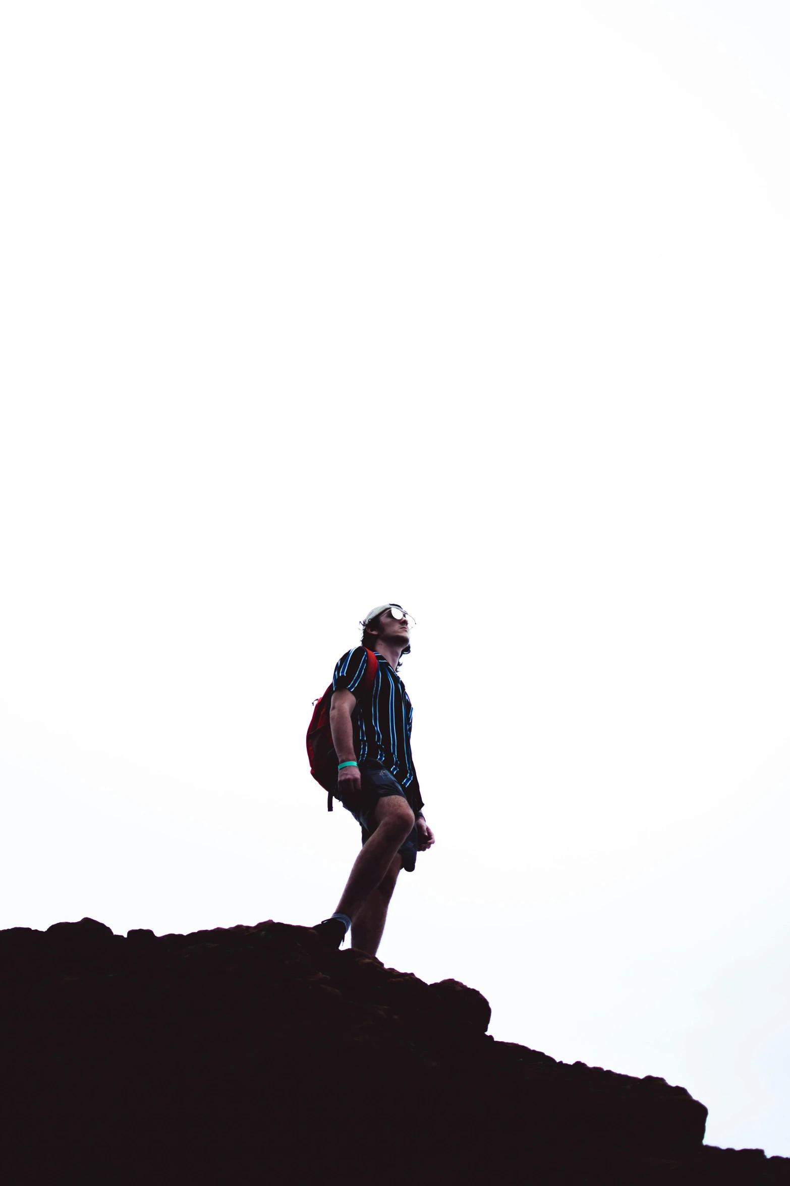 a man with a backpack standing on top of a mountain, by Byron Galvez, plain background, covered with tar. dslr, instagram photo, ( ( ( kauai ) ) )