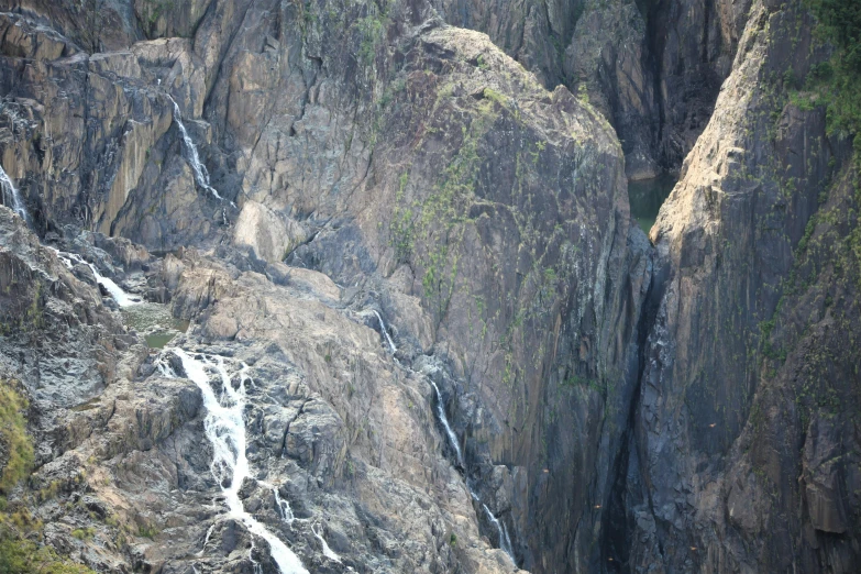 a group of people standing on top of a mountain next to a waterfall, helicopter view, “ iron bark, close - up photo, trending photo