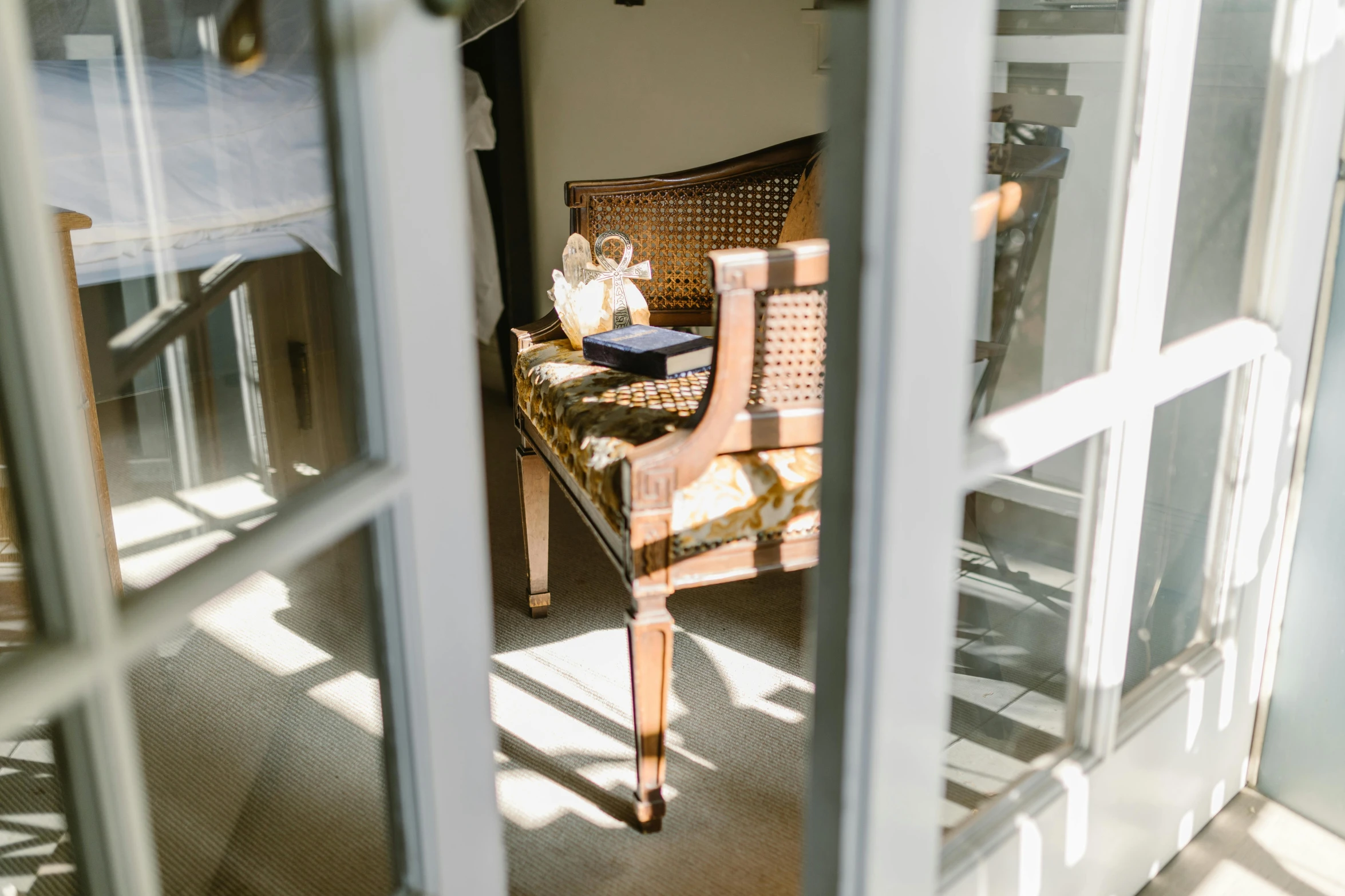 a teddy bear sitting on top of a chair in a living room, in the sun, french provincial furniture, french door window, gold and white robes