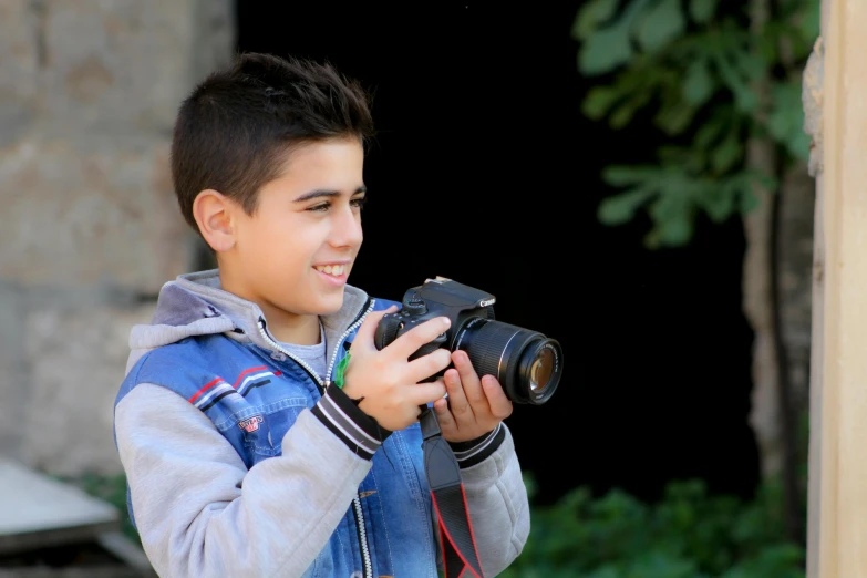 a young boy taking a picture with a camera, pixabay, amr elshamy, while smiling for a photograph, avatar image, outdoor photo