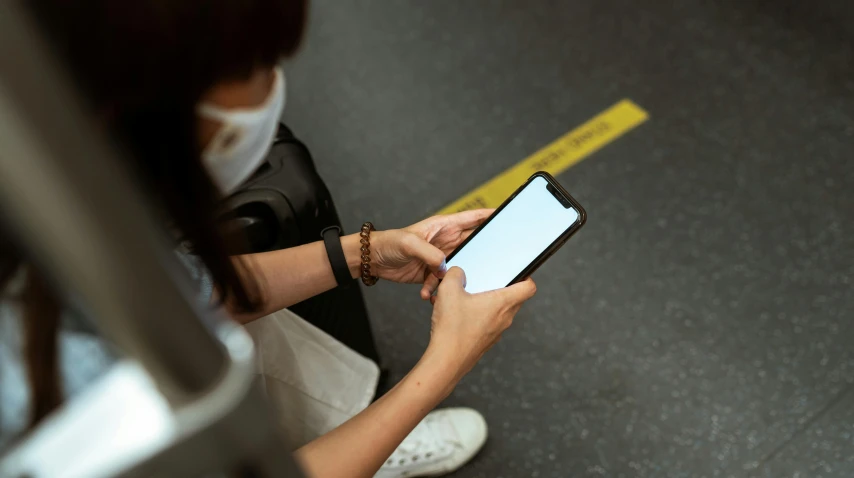 a close up of a person holding a cell phone, trending on pexels, square, black. airports, masking, so i advised her to get in line