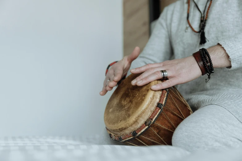 a close up of a person playing a drum, by Emma Andijewska, meditating, on a white table, background image, lute