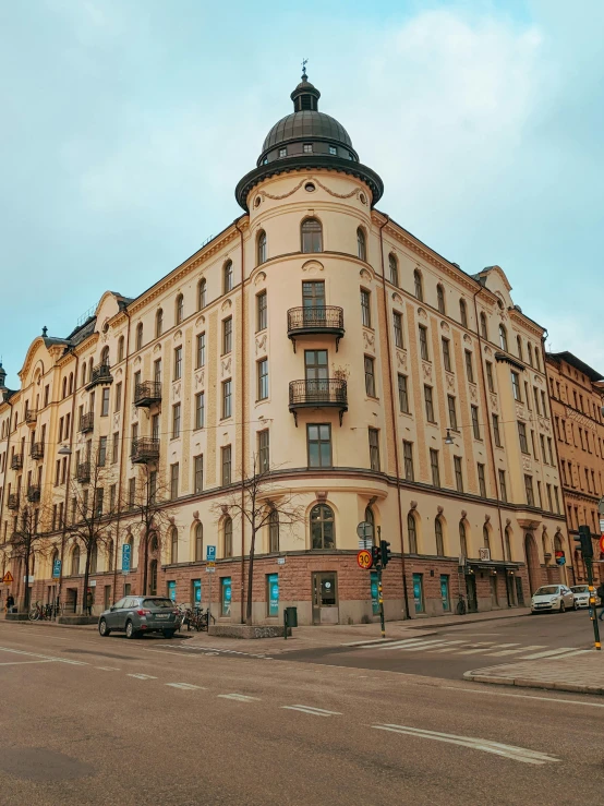 a large building sitting on the side of a road, by Tom Wänerstrand, pexels contest winner, art nouveau, stockholm city, 2 5 6 x 2 5 6 pixels, standing on street corner, panoramic view