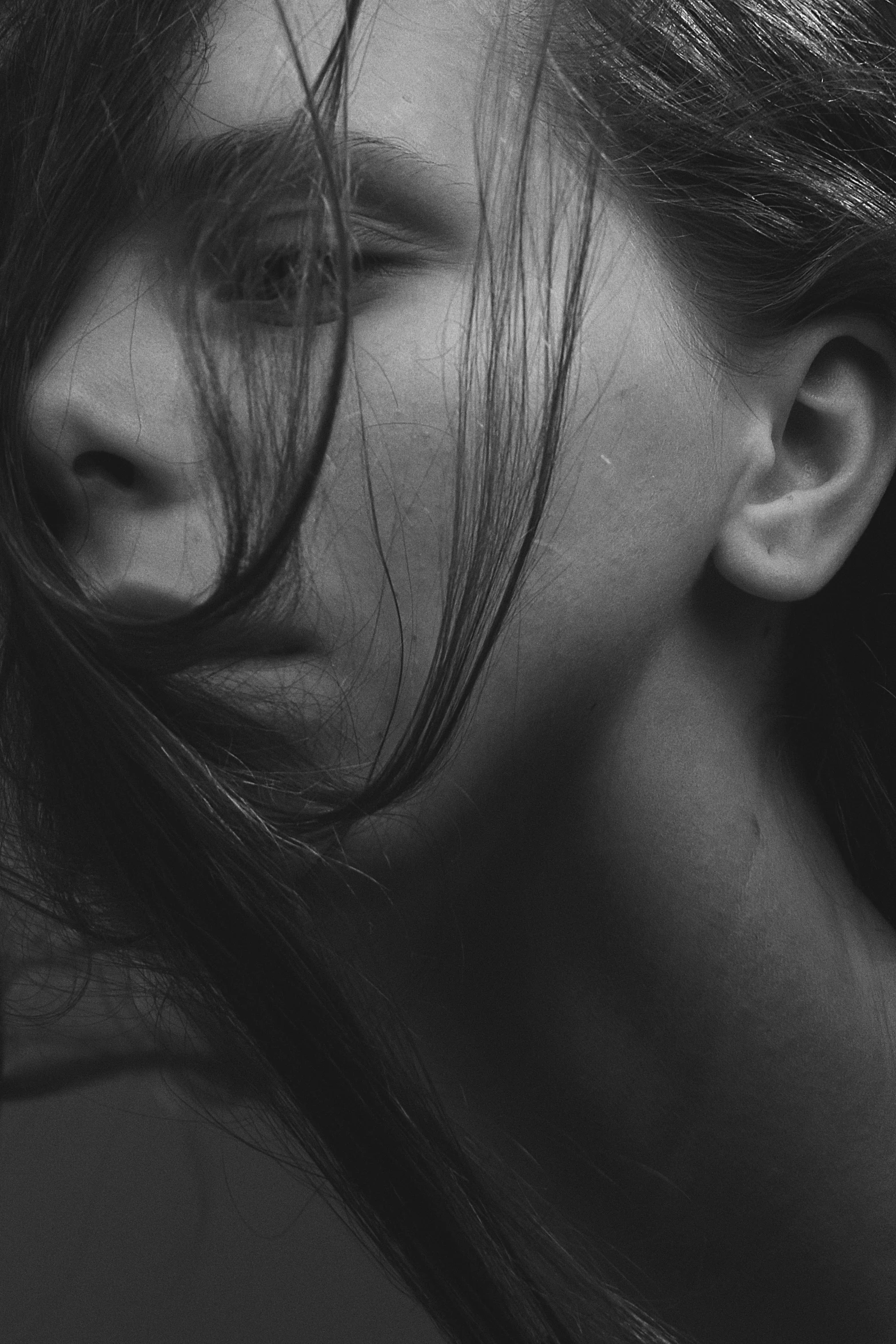 a woman with her hair blowing in the wind, a black and white photo, by Adam Marczyński, pexels contest winner, realism, exhausted face close up, noseless, girl with black hair, shy