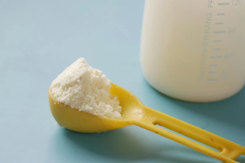 a spoon full of sugar next to a bottle of milk, unsplash, holding a yellow toothbrush, covered in white flour, high quality product image”