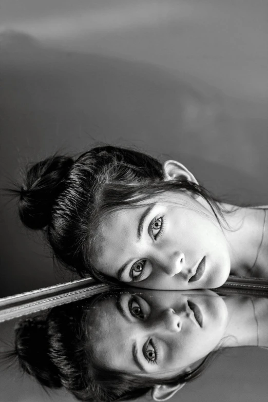 a black and white photo of two young girls, a black and white photo, by irakli nadar, pexels contest winner, hyperrealism, reflections on a glass table, young woman with long dark hair, panoramic view of girl, laying down