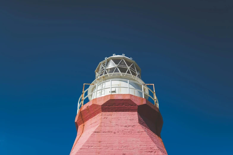 a red and white lighthouse against a blue sky, inspired by Wes Anderson, unsplash contest winner, picton blue, faded glow, low view, high details photo