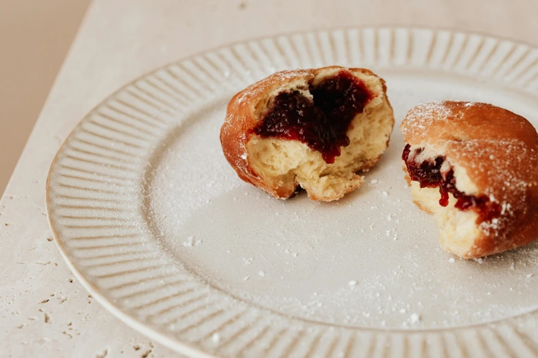 a couple of doughnuts sitting on top of a white plate, inspired by Richmond Barthé, unsplash, baroque, cut-away, maroon, battered, filling the frame