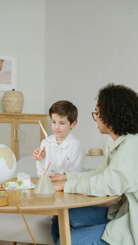 a woman sitting at a table with two children, pexels contest winner, visual art, geodesic dome, holding a white flag, boy with neutral face, gif